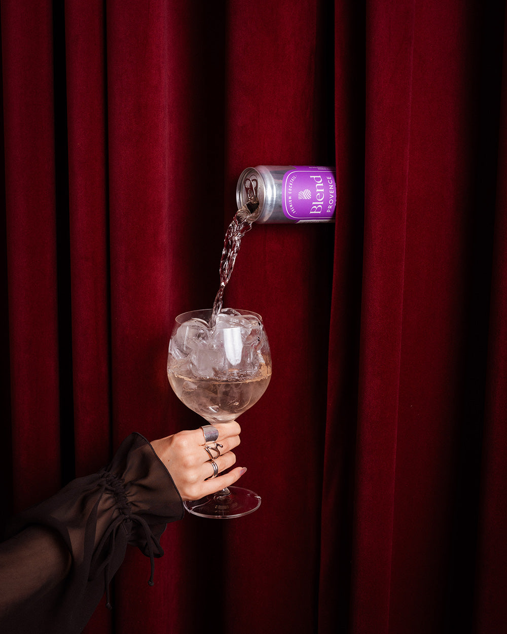 Blend Provence Spritz kaadetaan lasiin verhon takaa, käsi pitelee lasia jossa jäitä